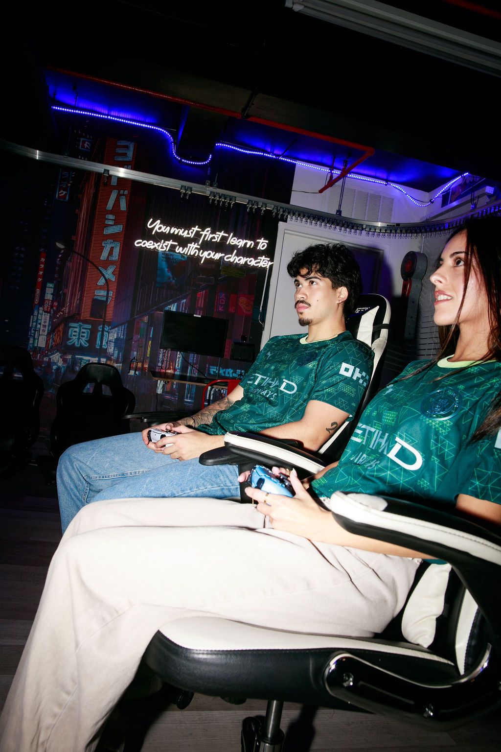 Two players in green Manchester City fourth kits gaming under blue lights