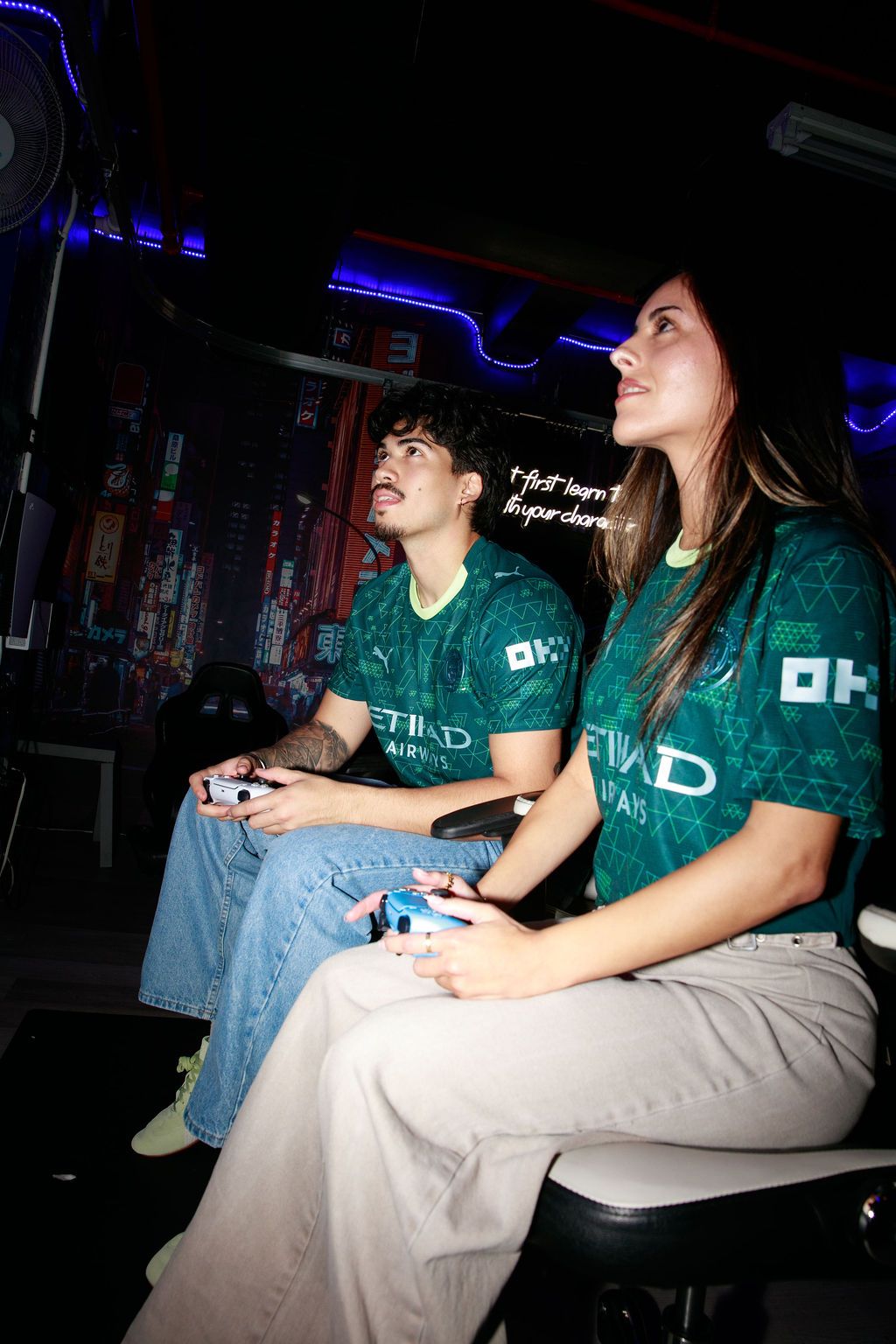 Players in green Manchester City kits holding game controllers